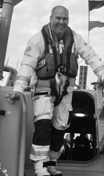 RNLI Peterhead lifeboat operations manager Jurgen Wahle smiling beside the boat. Image: RNLI.