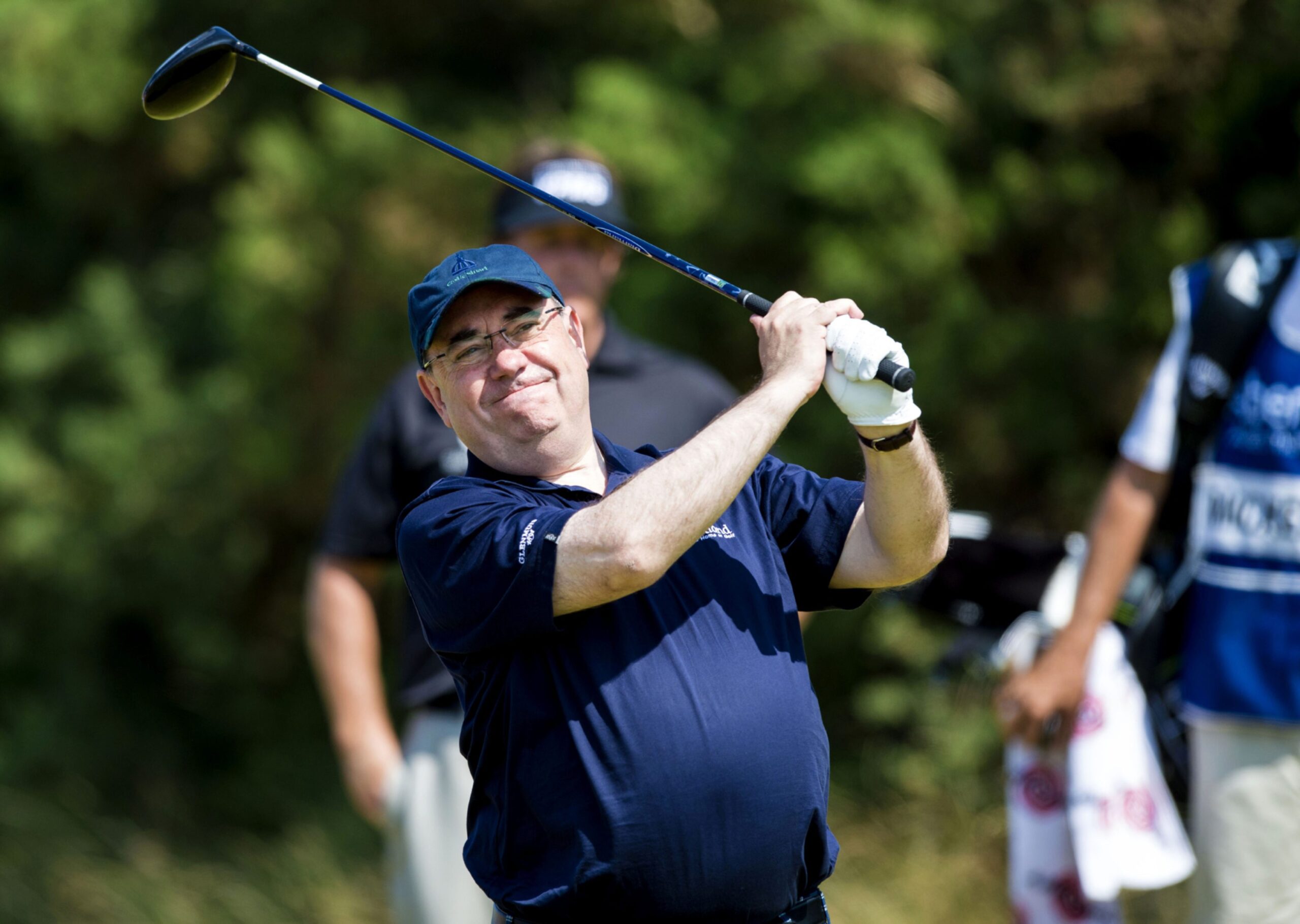 Alex Salmond dressed in dark blue watching his tee on the golf course.