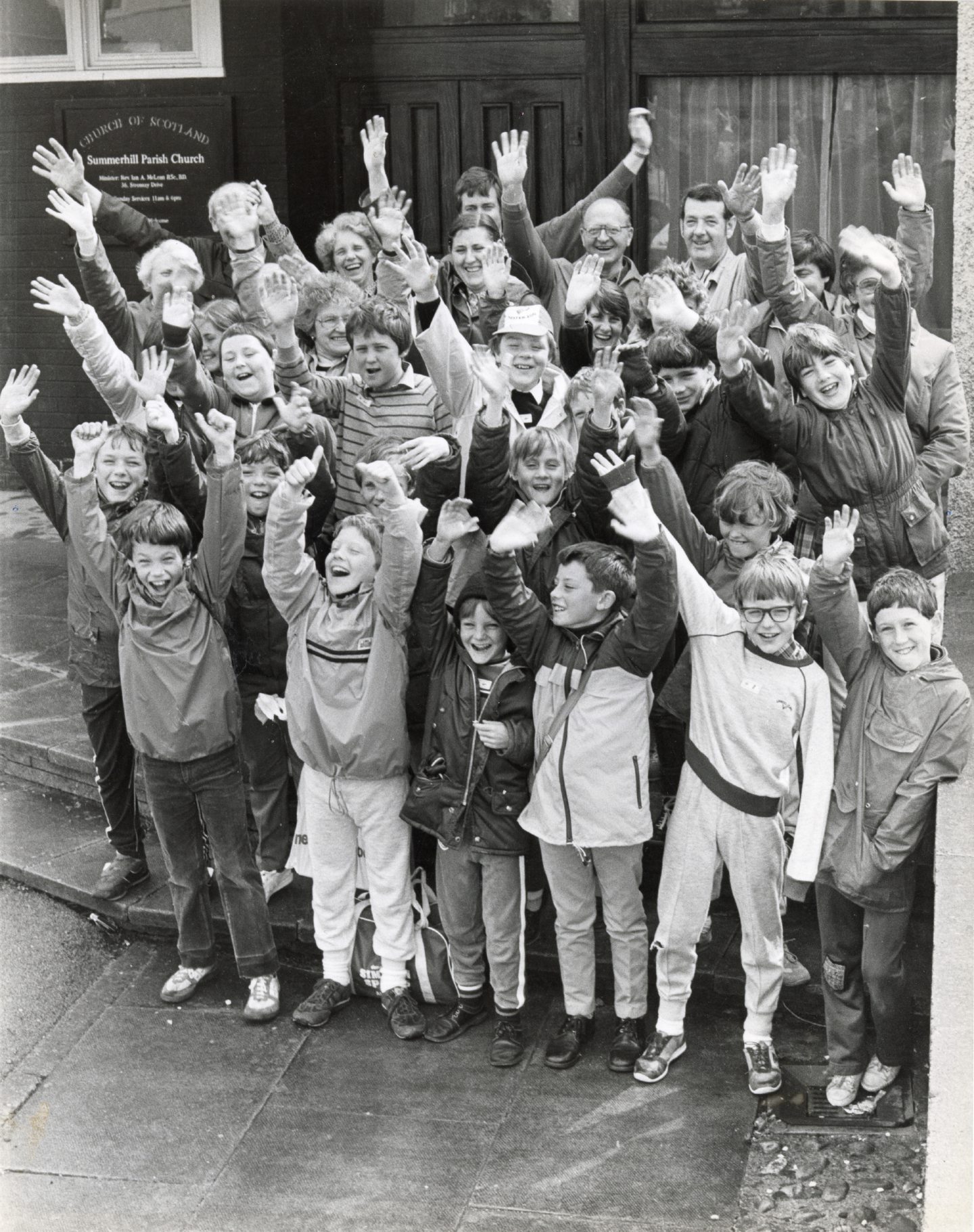 Image shows young members of the boys' brigade waving to the camera ahead of embarking on a sponsored walk.