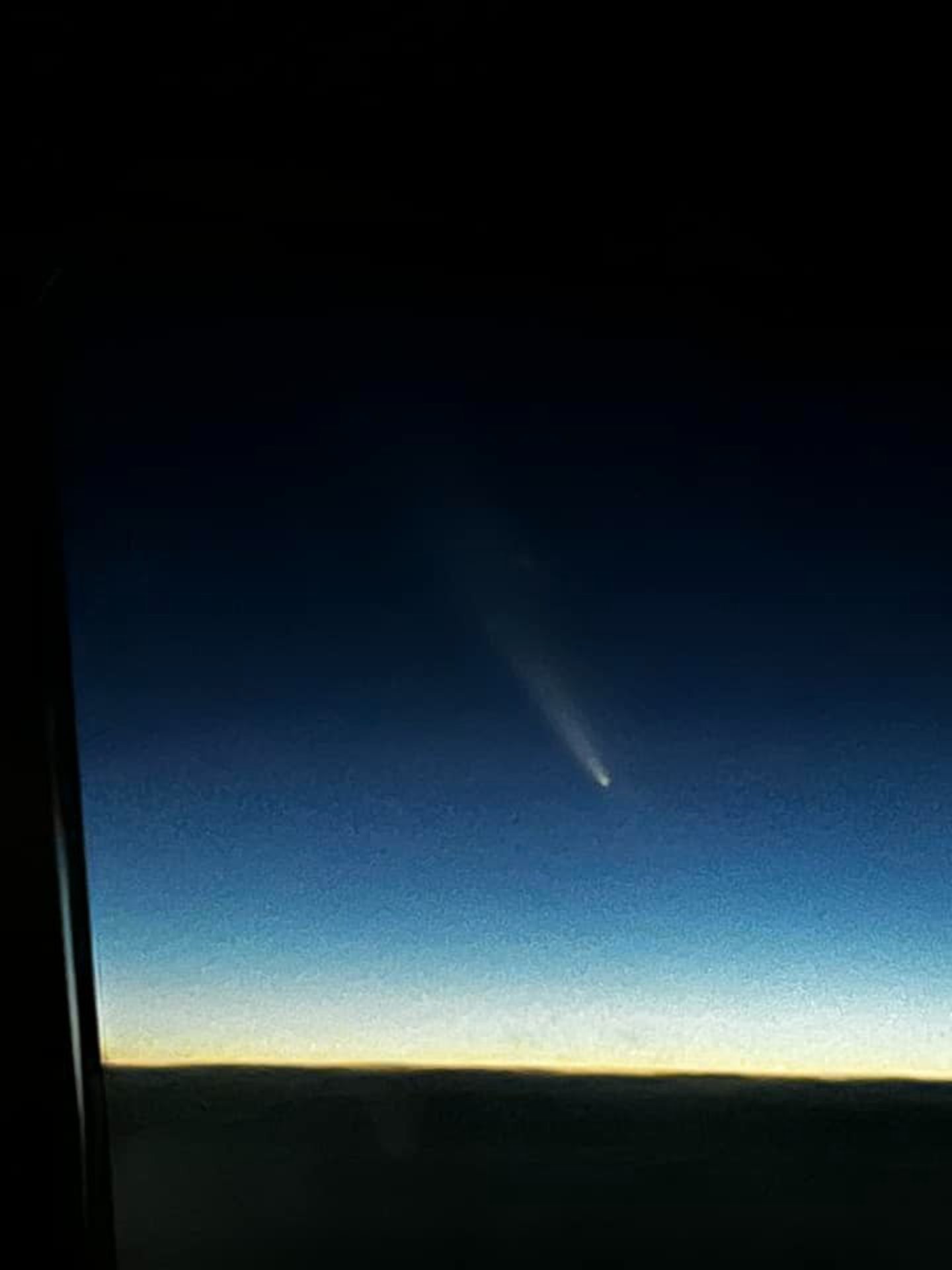 The comet pictured through a plane window