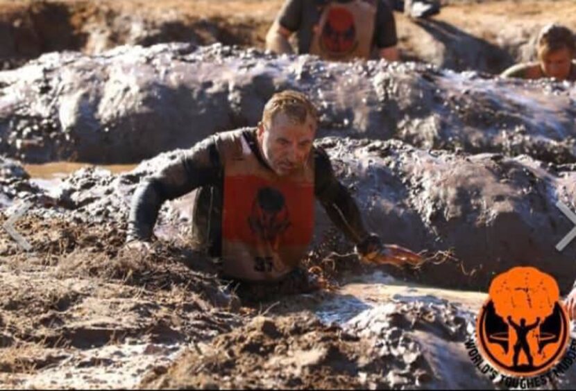 James Brown in a trench on an obstacle course at Worlds Toughest Mudder 2023.