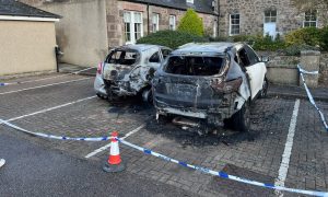 Burnt out cars behind police tape