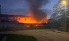 Property illuminated in orange as smoke rises from a fire in the back garden of a residential property,