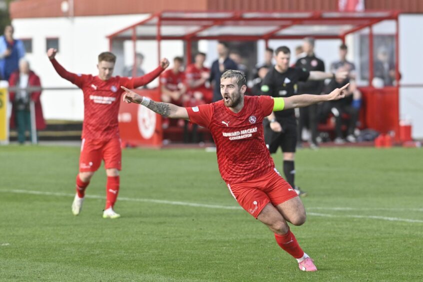 Brora player Jordan MacRae spreads his arms wide after scoring for his club