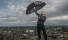 Reporter David Mackay holding an umbrella on Ladyhill in Elgin.