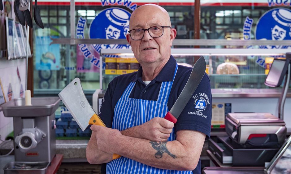 Michael Dawson holding butcher knives crossed on chest. 