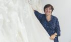 Christine Fraser holding a wedding dress.