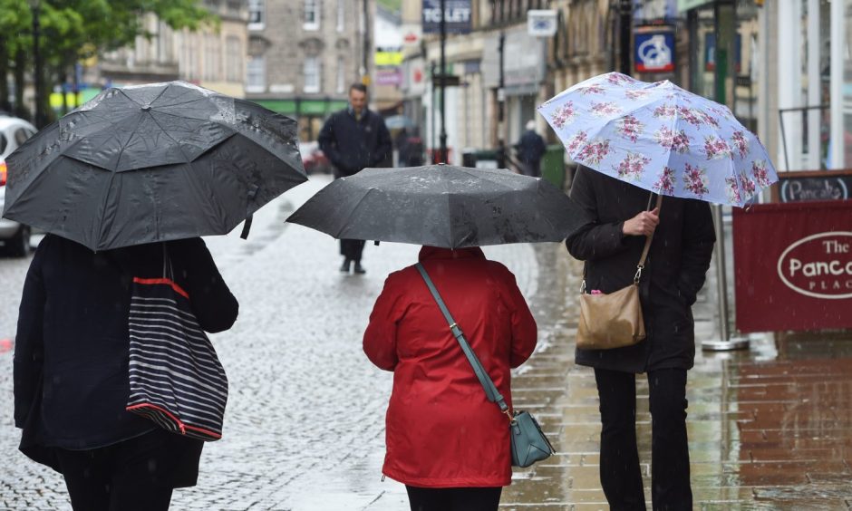 Shoppers in Elgin under umbrellas. 