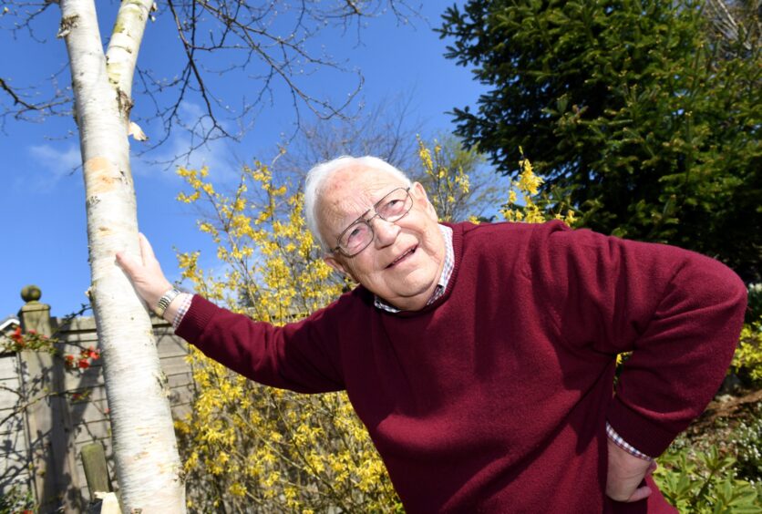 Former Beechgrove Garden presenter Jim McColl in a wine jumper leaving against a tree. 