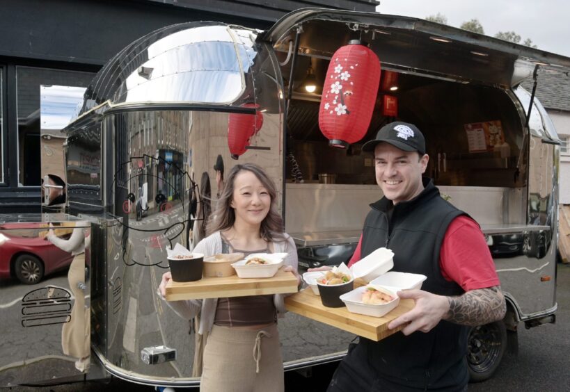 Karen and JP Saint holding trays of food at the Mei Mei food truck in Inverness