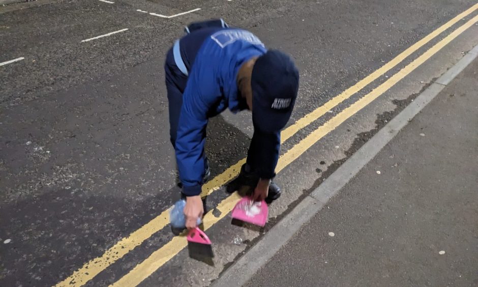 Street pastor sweeping up glass. 