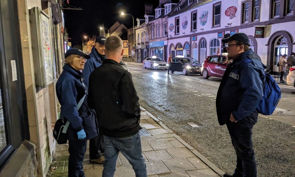 Street pastors chatting to man on Elgin High Street.