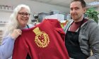 Lee Midlane and Matt Cassells holding up red Dandy Lion hoodie.