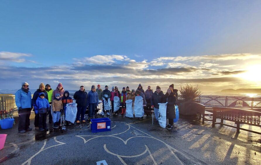 Volunteers holding bags of rubbish on a Paws on Plastic beach clean.