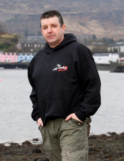 Ross Cowie standing by the waters edge wearing a black jumper