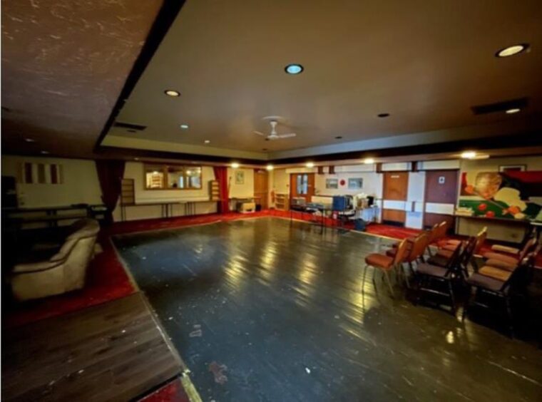 Bright room with a large dancefloor and chairs dotted around the room.