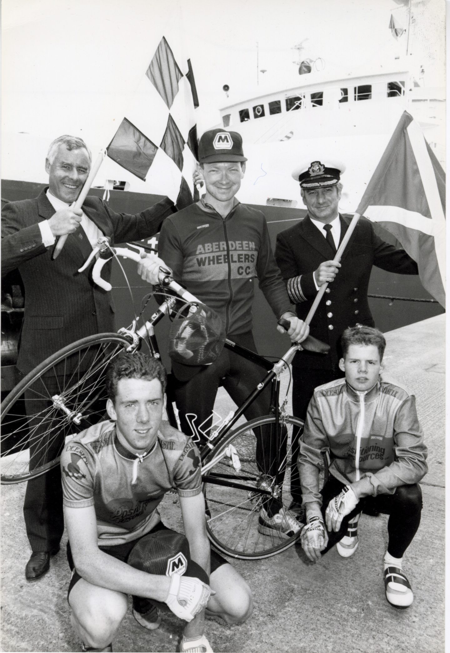 Three men holding flags and two cyclists