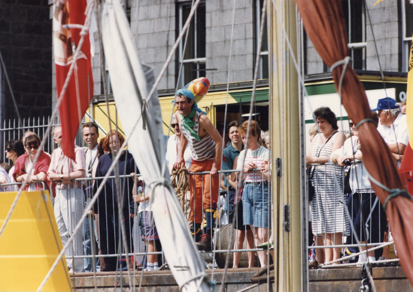 A man with a massive parrot balloon on his shoulder leaning over a railing