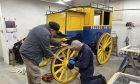 Grampian Transport Museum volunteer Mike Rasmussen adding coach lines and final touches to the 1901 omnibus, while trustee Kevin McCormick turns the wheel. Image: Kirstie Waterston