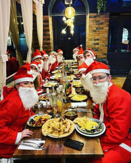 People dressed as Santa at a table.