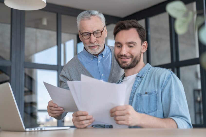 father and son looking at at paperwork together