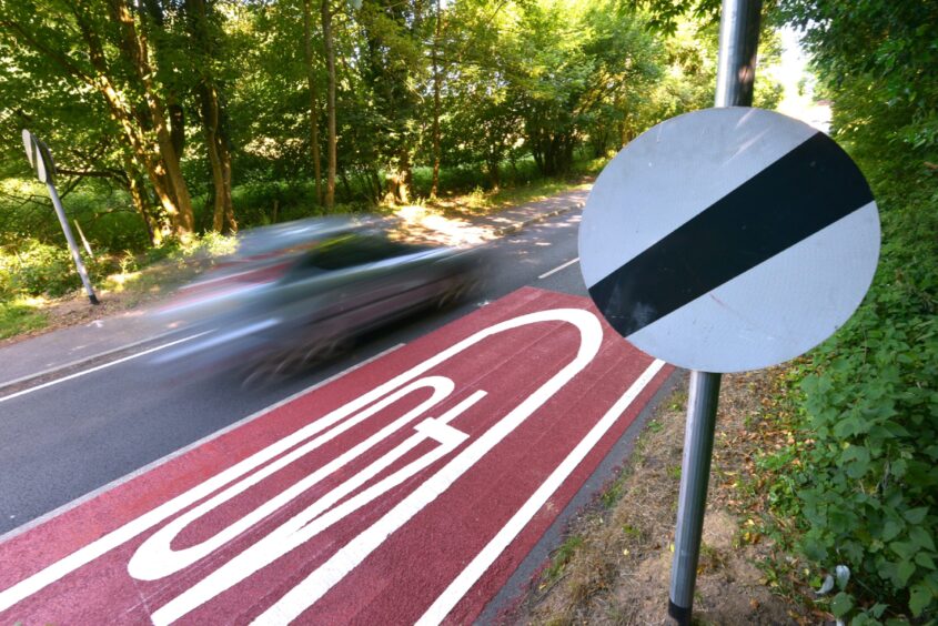 Speeding car going past a national speed limit sign.