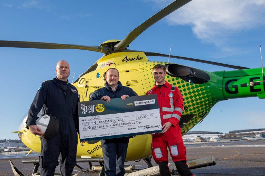 Press and Journal Editor Craig Walker presents the cheque for the Scottish Charity Air Ambulance to pilot Pete Winn and paramedic Keir Lynch. 