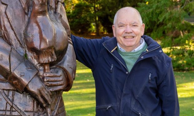 Alan James leaning on wooden piper.