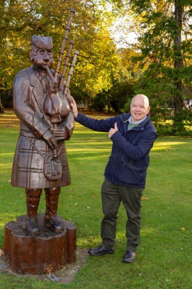 Alan James with wooden piper statue. 