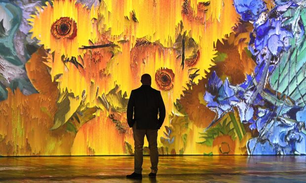 Man in immersive exhibition looks at the sunflower painting