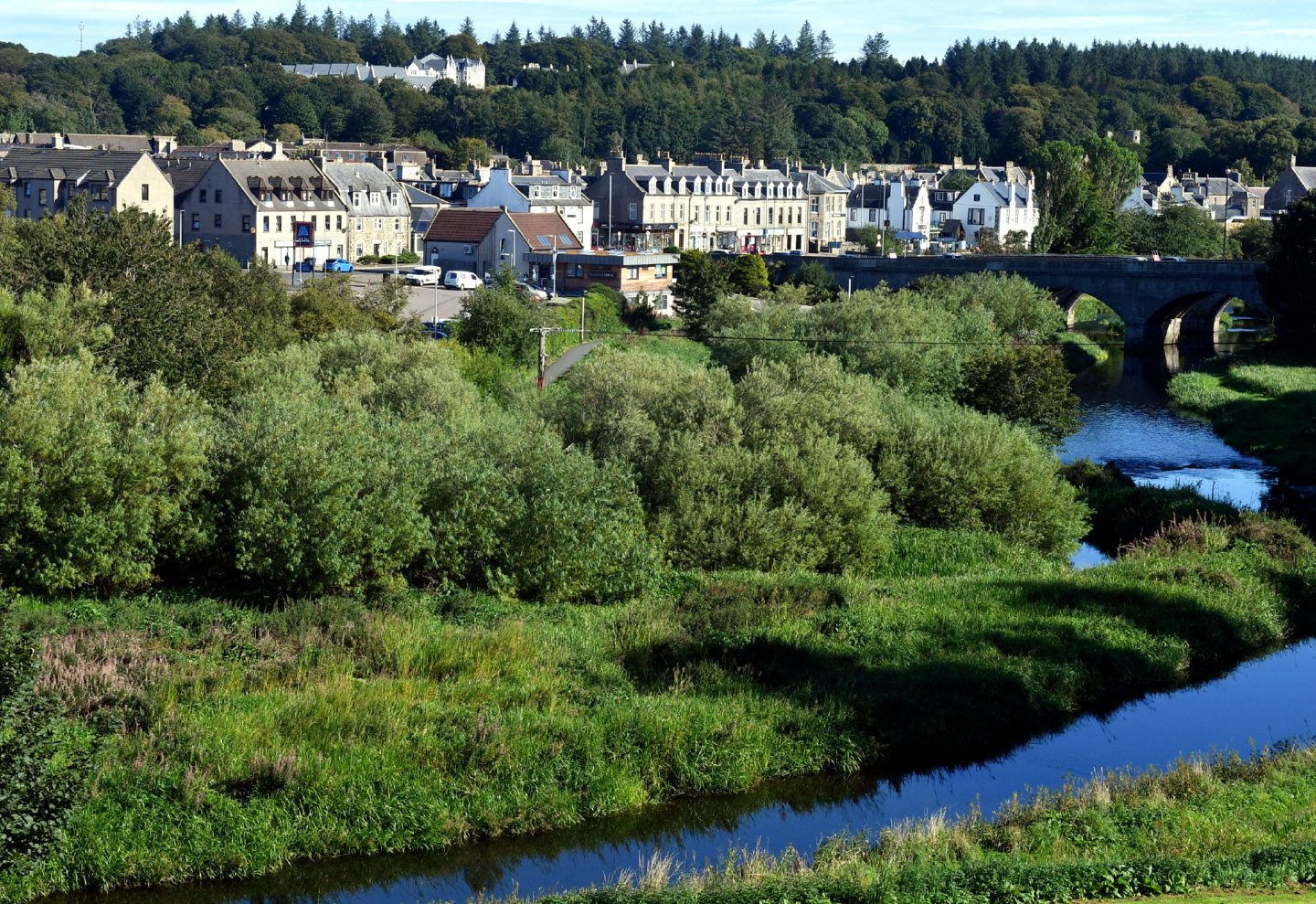 Ellon on a sunny day with trees and the River Ythan in the foreground.