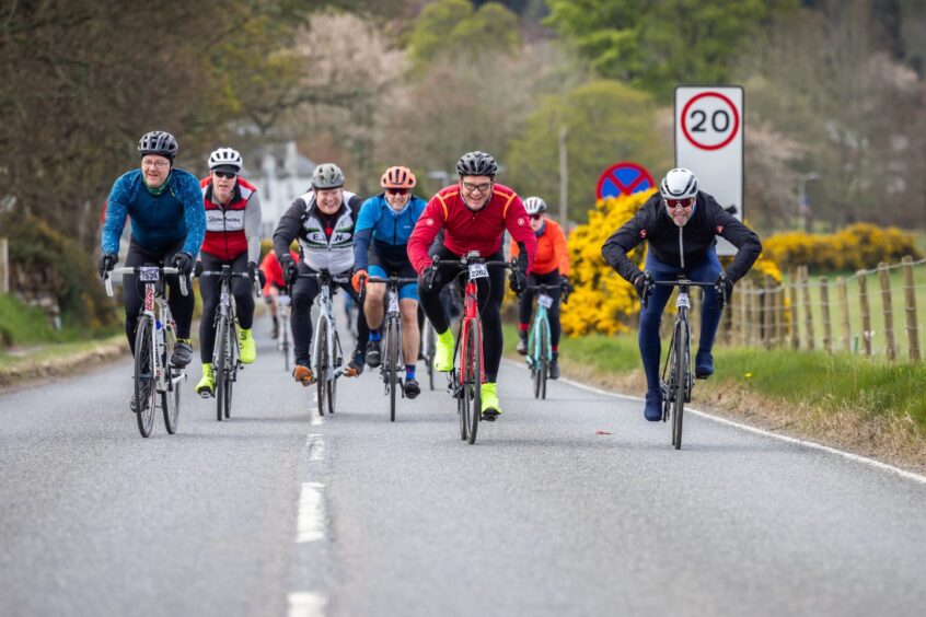 Cyclists riding along street during Etape Loch Ness.