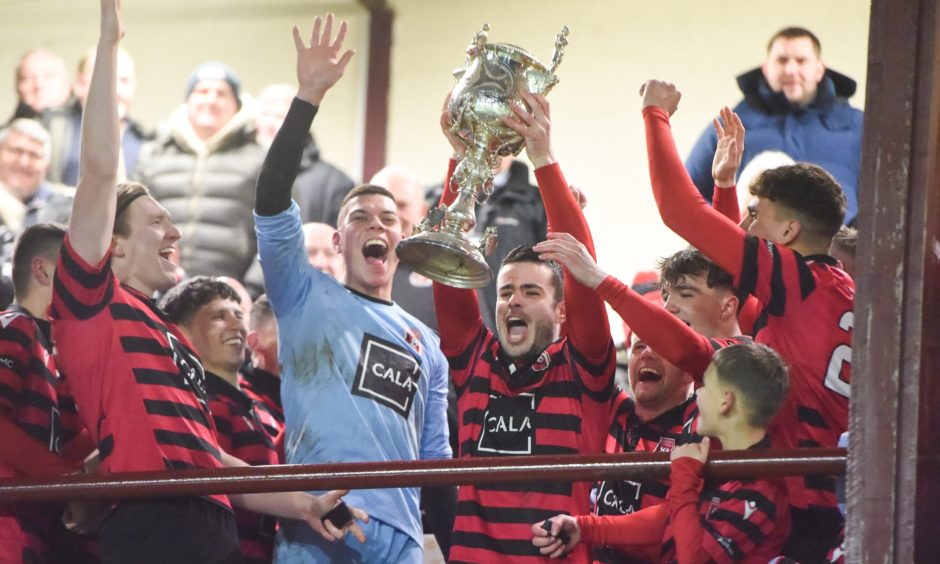 Inverurie Locos' Calum Dingwall is surrounded by his team-mates as he lifts the Aberdeenshire Cup trophy in 2024.