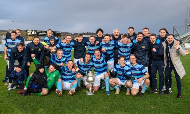 Banks o' Dee's players and management team celebrate with the Evening Express Aberdeenshire Cup after their victory against Huntly. Photos by Kami Thomson/DCT Media.