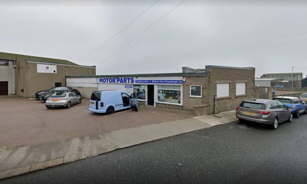 Blue van and cars sit outside and down the side of Motor Parts in Fraserburgh.