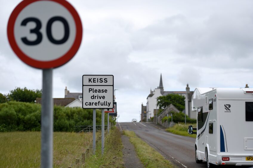 Motorhome driving towards Keiss with a 30mph road sign and a Keiss welcome sign to the left of the road.