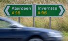 Busy traffic speeding past Inverness and Aberdeen sign posts on the A96 at Gollanfield between Inverness and Nairn.