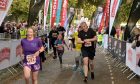 Runners dressed in colourful active wear cross the finish line in Inverness during Loch Ness Marathon