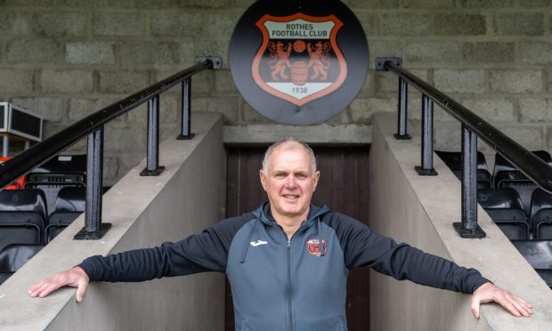 Rothes manager Ronnie Sharp stands in the tunnel at Mackessack Park with his arms outstretched.