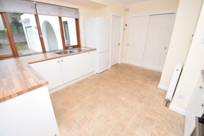 Open kitchen space with white units and wood worktops. 