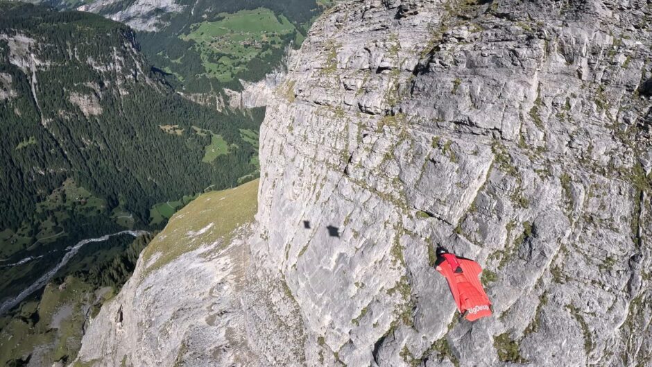 Liam Byrne base jumping next to cliff face 