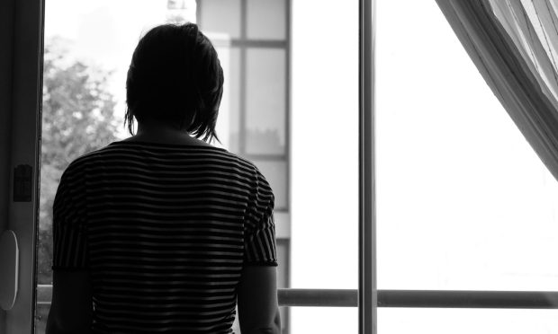 Silhouette of a woman looking out a window.