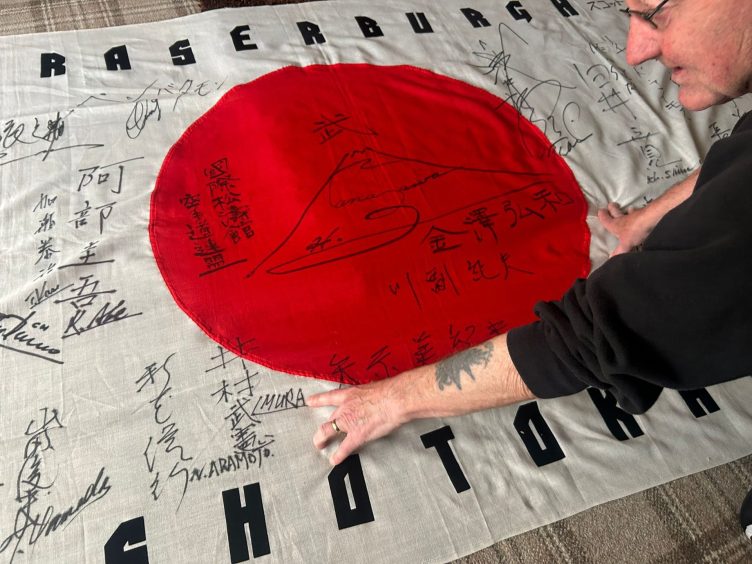 Sandy walks me through each of the signatures on his decades-old flag. Image: Isaac Buchan/ DC Thomson