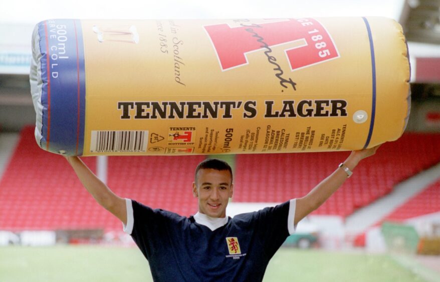 Rachid Belabed holds up a giant, inflatable can of lager at an Aberdeen FC photocall ahead of the Scottish Cup final in 2000.