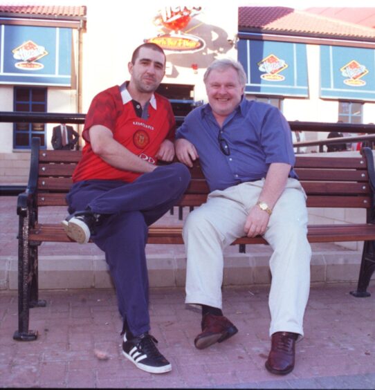 An Eric Cantona lookalike pictured on a bench with the real-life version of Aberdeen FC legend Joe Harper.