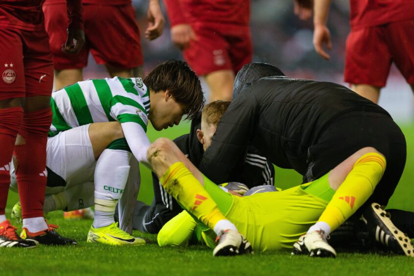 Aberdeen's Ross Doohan lies on the pitch following a collision with Celtic's Kyogo Furuhashi (L).