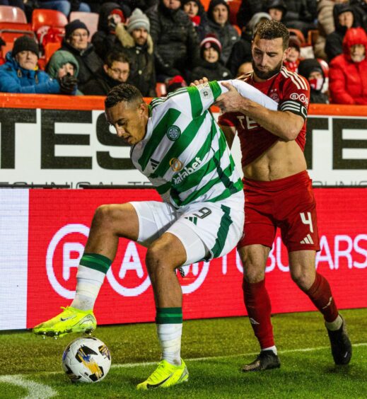 Celtic player Adam Idah shields the ball at the corner flag from Aberdeen captain Graeme Shinnie.