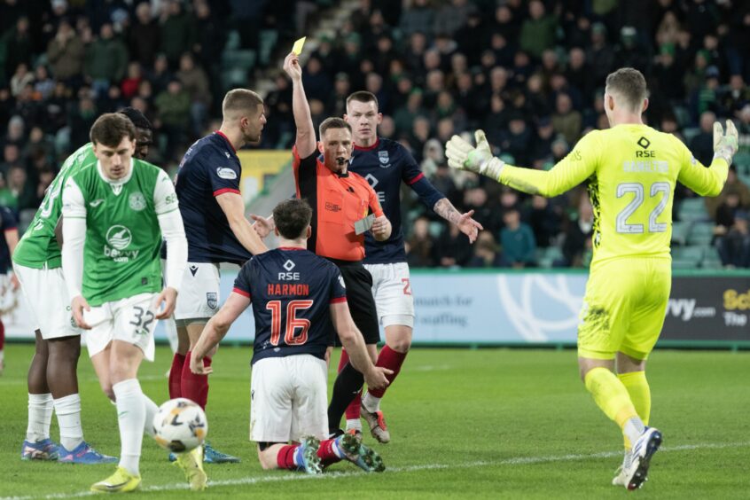 Referee Lloyd Wilson shows a yellow card to Ross County's George Harmon after his foul on Dwight Gayle led to Hibs' first penalty, which goalkeeper Jack Hamilton saved before Elie Youan scored from the spot a few minutes later.