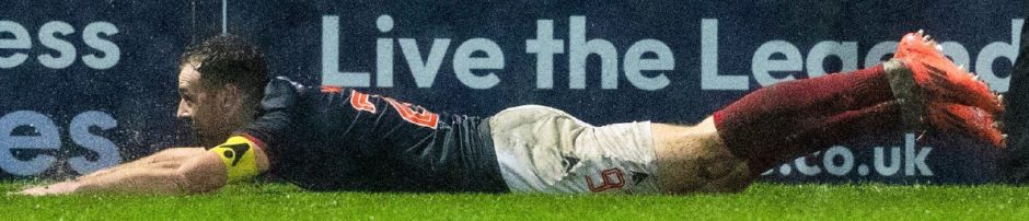 Ross County attacker Jordan White slides in the rain to celebrate his late leveller in the 2-2 draw against Hearts in the SPFL Premiership on December 29, 2024, at the Global Energy Stadium, Dingwall. 