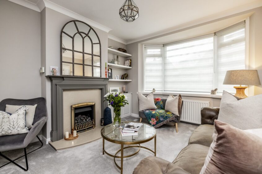 living room with fireplace, arched mirror and bay window at this Mannofield property